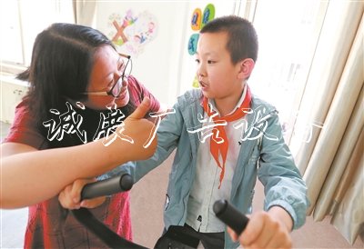 在無錫市廣新小學(xué)融合教育資源中心，梁溪區(qū)特教指導(dǎo)中心資源教師陳向華指導(dǎo)小過進(jìn)行康復(fù)訓(xùn)練，夸贊他有進(jìn)步。