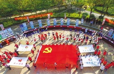 2019年10月19日，上海開展“不忘初心、牢記使命”黨員志愿者先鋒行動，“兩新”黨員志愿者在公園廣場托起一面黨旗。? 光明日報 圖