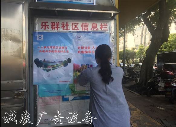 圖為社區(qū)工作人員在宣傳欄粘貼創(chuàng)城海報